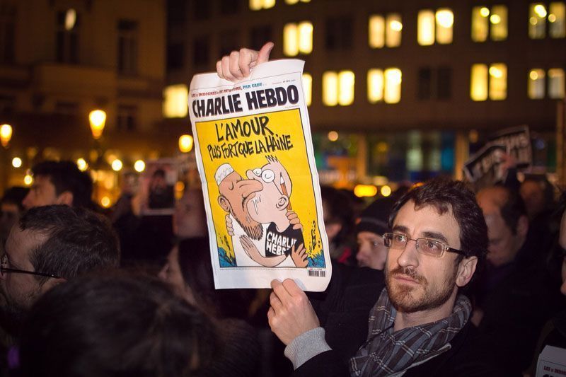 Manifestante con un ejemplar de Charlie Hebdo en la Plaza Luxemburgo de Bruselas (Bélgica). En el ejemplar se lee: "el amor es más fuerte que el odio" | Foto: Valentina Calà en Flickr